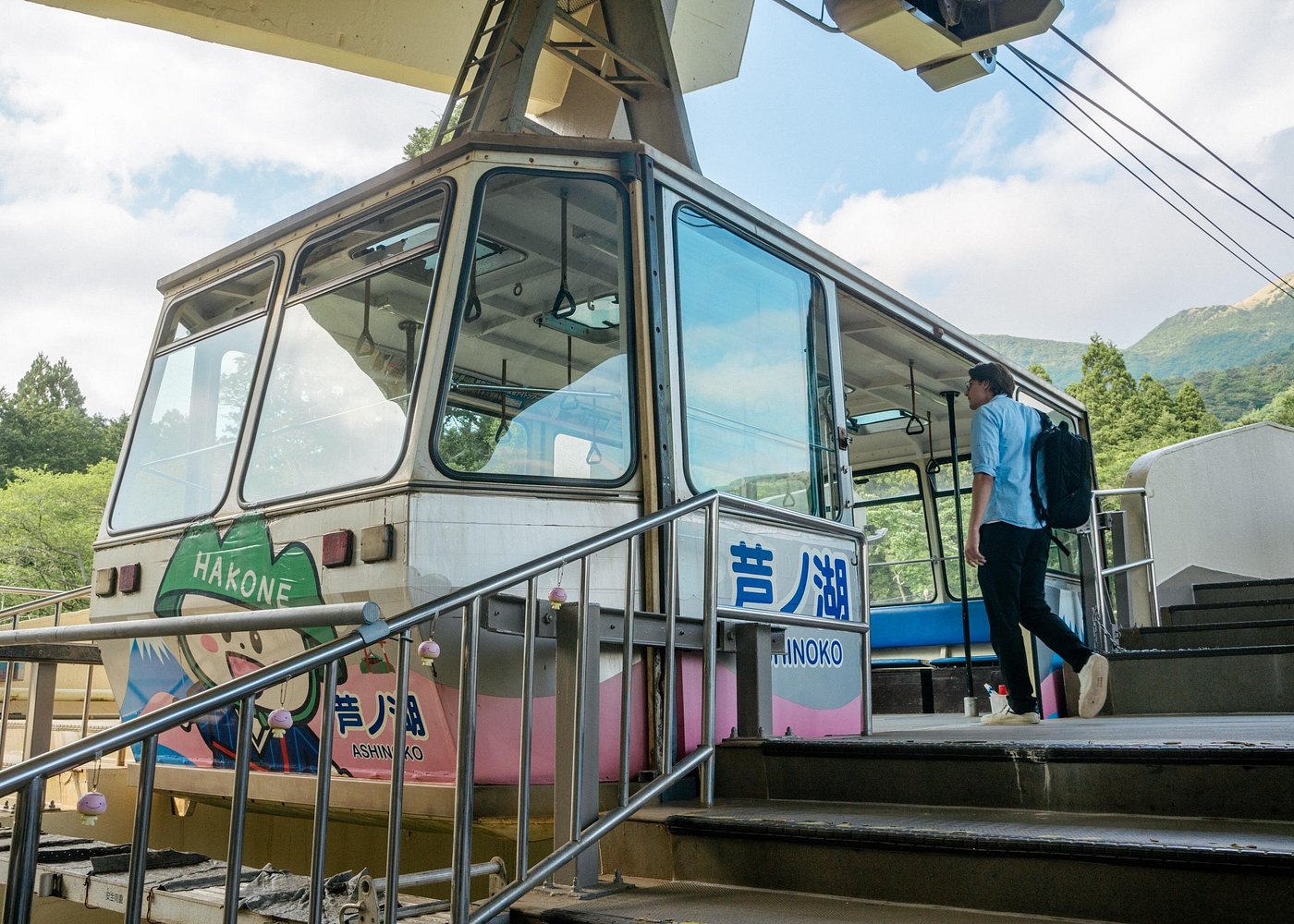 Hakone Ropeway cabin marked Ashinoko, with a traveler boarding at the lakeside station